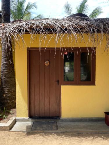 a small yellow house with a thatched roof at MKS - Kite & Wing Foil camp in Kalpitiya