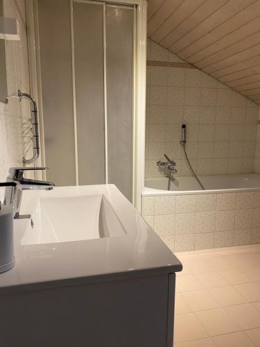 a white bathroom with a sink and a tub at Appart' dans maison villageoise in Boudry