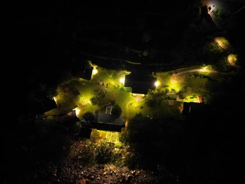 an aerial view of a house at night with lights at Thehraav By The River - Mudhouse Odyssey, Tirthan Valley in Banjār