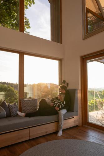 a woman sitting on a couch in a room with windows at steiRerBLiCke - Winzerhäuser an der südsteirischen Weinstraße in Glanz an der Weinstraße 