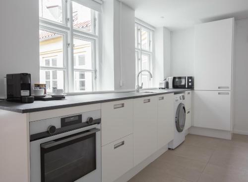 uma cozinha branca com um lavatório e uma máquina de lavar louça em Beautiful 2-bed in top Copenhagen location em Copenhague