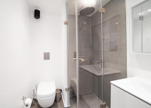 a white bathroom with a shower and a toilet at Fantastic 2-bed apartment with balcony in Odense
