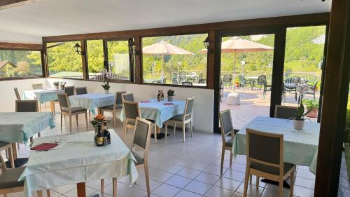 - une salle à manger avec des tables, des chaises et des fenêtres dans l'établissement Albergo Stella Alpina, à Tenno