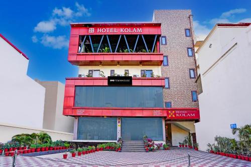 ein Hotel mit einer roten Fassade und einem Balkon in der Unterkunft Townhouse Prince Chowk Near Railway Station in Dehradun