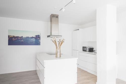 a white kitchen with a vase of flowers on a counter at Fantastic 1-bed apartment w private terrace in Aarhus