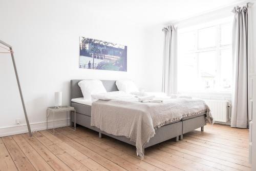 a white bedroom with a bed with white sheets at Beautiful 2-bedroom apartment with a large balcony in Nørrebro - 65 in Copenhagen