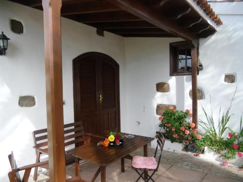 porche con mesa de madera, sillas y puerta en Your Island Finca El Picacho C, en Tegueste