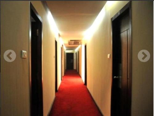 einen Flur mit rotem Teppich und einem langen Korridor in der Unterkunft Hotel Vip International in Kalkutta