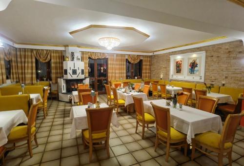 un restaurante con mesas blancas y sillas amarillas en Hotel Kärntnerhof & SeeBlick Suiten en Presseggersee