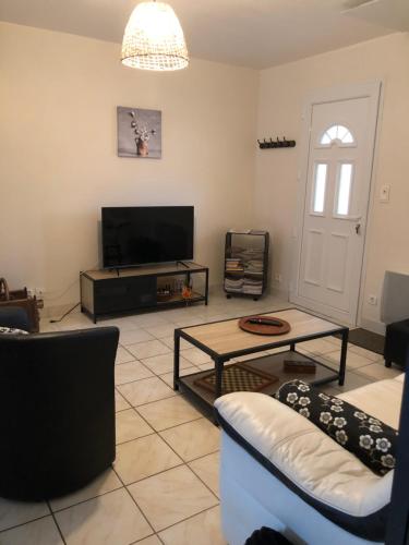 a living room with a tv and a couch and a table at Gîte “Les reflets de la Charente” in Condac