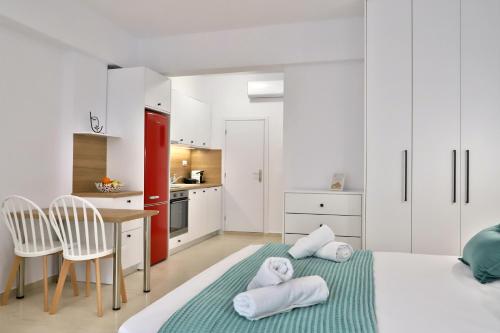 a white room with a bed and a kitchen at Centro Apartments by Comfortbnb- Sitia in Sitia