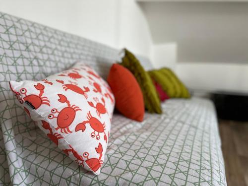 - un canapé blanc avec des oreillers rouges dans l'établissement La little white house, à Cayeux-sur-Mer