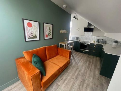 a living room with an orange couch and a kitchen at Brantwood Apartments - Apartment 3 in Manchester