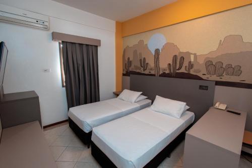 una habitación de hotel con 2 camas y un cuadro en la pared en ibis Styles Presidente Prudente Portal D'Oeste, en Presidente Prudente