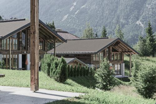 ein großes Holzhaus mit einem Berg im Hintergrund in der Unterkunft IM WEIDACH Superior Chalets in Leutasch
