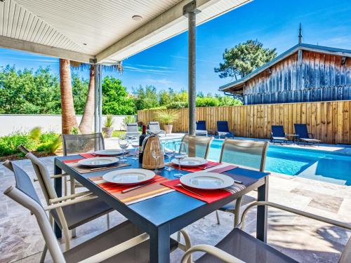 una mesa y sillas en un patio con piscina en Villa Plein Air by Interhome, en Gujan-Mestras