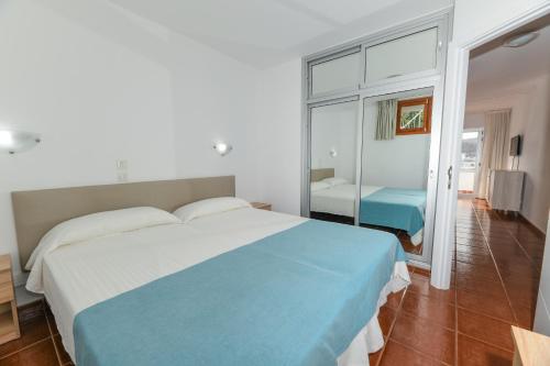 a bedroom with a blue and white bed and a mirror at Apartamentos LIVVO Puerto Bello in Puerto Rico de Gran Canaria
