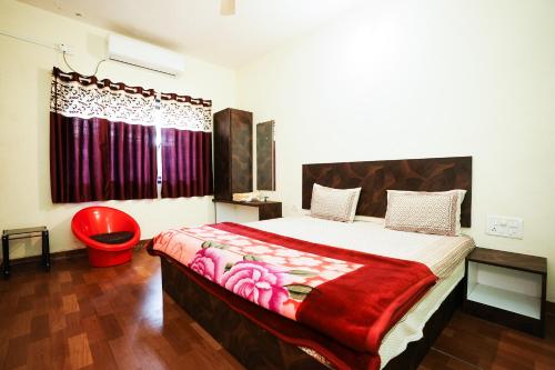 a bedroom with a large bed with a red blanket at Springfield Family Apartment in Mahabaleshwar