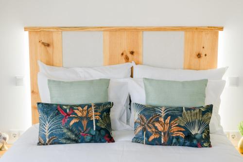 a bed with two pillows and a wooden headboard at Casa Ti'Rosa in Caniço