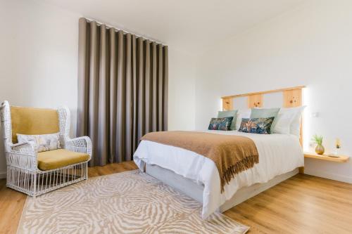a bedroom with a bed and a chair at Casa Ti'Rosa in Caniço