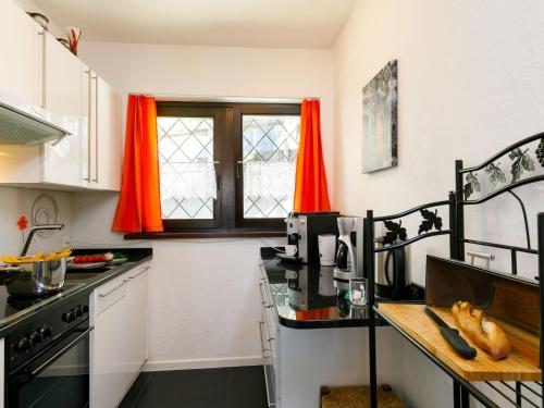 - une cuisine avec des rideaux rouges et un comptoir noir dans l'établissement Apartment Residence Miralago - Utoring Apt- D32 by Interhome, à Piazzogna