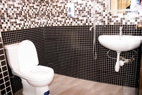 a bathroom with a toilet and a sink at Latitude Lukozi Hotel in Hambayo