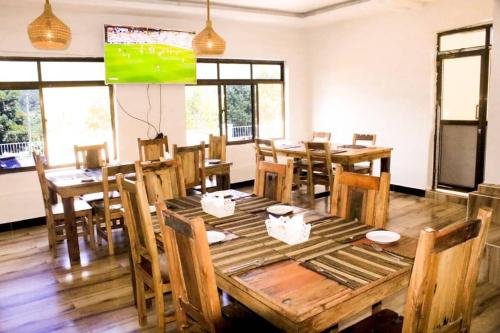 a dining room with wooden tables and chairs and a screen at Latitude Lukozi Hotel in Hambayo