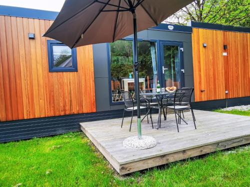a table and chairs with an umbrella on a deck at Holiday Home Tiny Haus Christas Angler-Oase by Interhome in Riedenburg