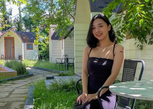 a woman in a black dress sitting at a table at Cottage Retreat DALAT in Da Lat
