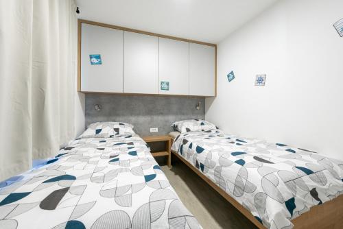 two beds in a small room with white cabinets at Luxury mobile home HIMALAJA, Oaza mira, Drage in Drage