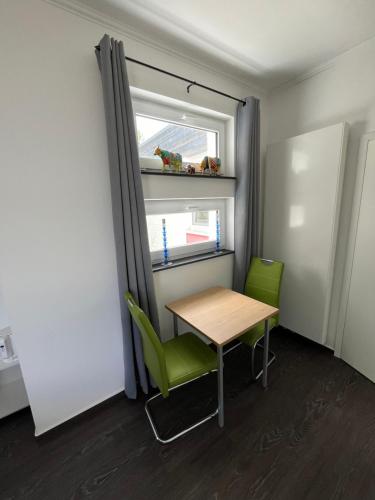 Cette petite chambre comprend une table et deux chaises vertes. dans l'établissement Marys Guestroom, à Goch