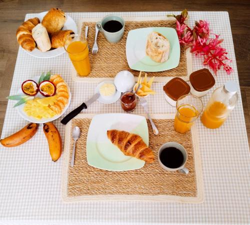 einen Tisch mit Frühstücksteller und Getränken in der Unterkunft Les Balisiers du Sud in Saint-Joseph