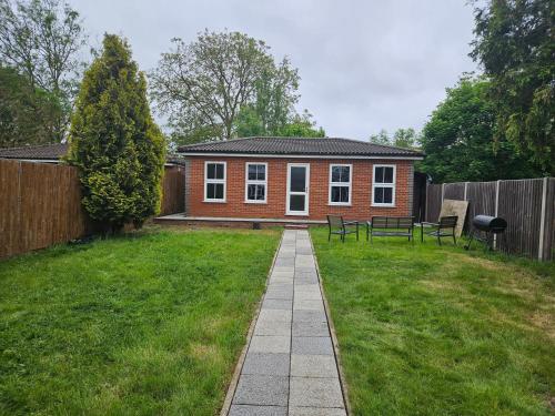 a small red brick house in a yard at Large Annexe with games room pool table ping pong air hockey movie projector in Windsor