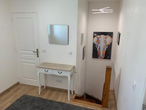 Cette chambre blanche dispose d'une table et d'un miroir. dans l'établissement Sweet villa au vue à mer, à Trouville-sur-Mer