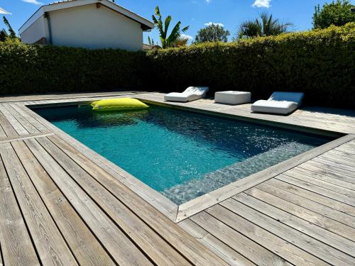 een klein zwembad met een houten terras bij Maison vacances Bassin d'Arcachon in Gujan-Mestras