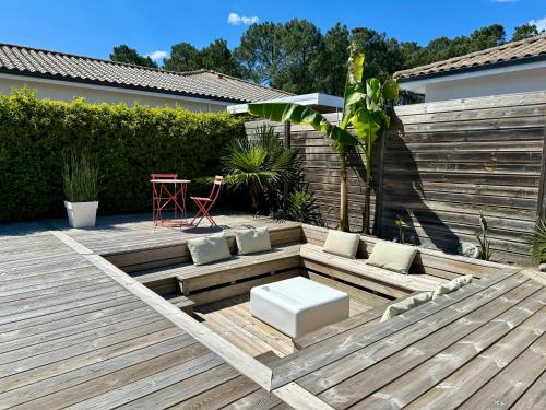 een tuin met een houten terras met een tafel en stoelen bij Maison vacances Bassin d'Arcachon in Gujan-Mestras