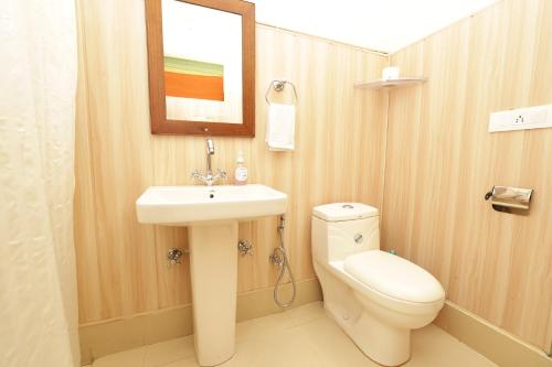 a bathroom with a toilet and a sink and a mirror at Thehraav By The River - Mudhouse Odyssey, Tirthan Valley in Banjār