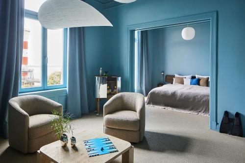 a bedroom with blue walls and a bed and chairs at stilwerk Strandhotel Blankenese in Hamburg
