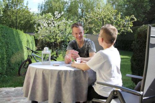 un hombre y un niño sentados en una mesa en Ferienwohnung im Hof Objekt ID 12111-0 en Waren