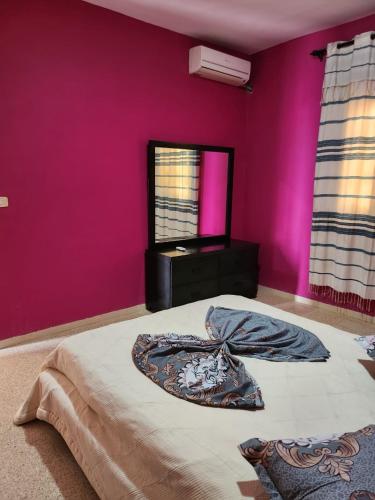 1 dormitorio con 1 cama con pared de color rosa en Prince, en Midoun
