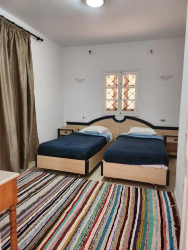 2 camas en un dormitorio con alfombra en Prince, en Midoun