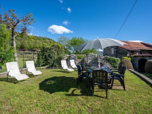 une table, des chaises et un parasol dans l'herbe dans l'établissement Holiday Home Monte San Giulio by Interhome, à Pella