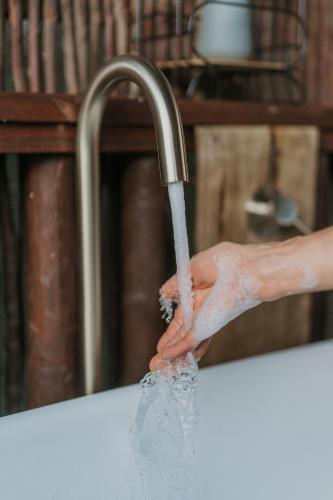 a person is washing their hands under a water faucet at Thunzi Bush Lodge in Beachview