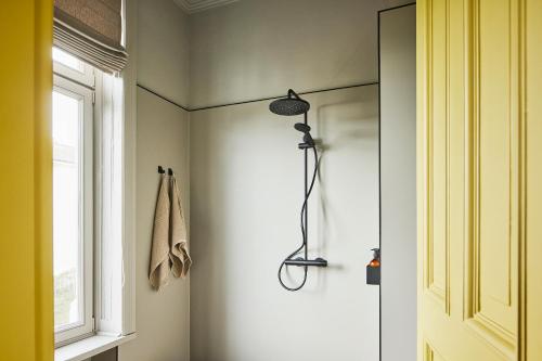 La salle de bains est pourvue d'une douche avec une porte en verre. dans l'établissement stilwerk Strandhotel Blankenese, à Hambourg
