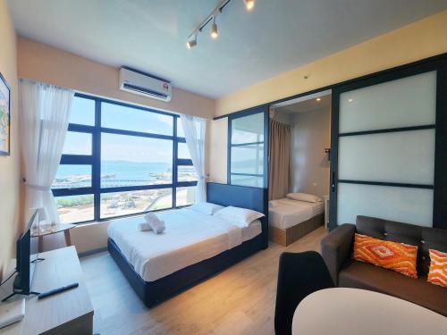 a bedroom with a bed and a tv and a couch at Jesselton Quay Kota Kinabalu City Centre by LW Suites in Kota Kinabalu