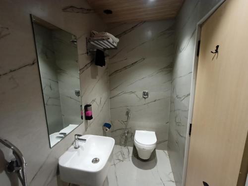 a white bathroom with a sink and a toilet at Hotel Golden Suites - Near Nesco in Mumbai
