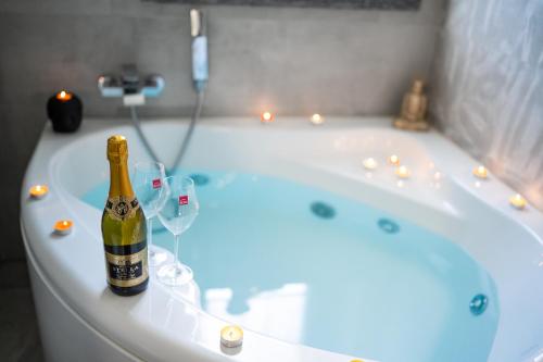 a bottle of champagne sitting on a bath tub with wine glasses at Idromassaggio Doppia - Ango House Seregno in Seregno