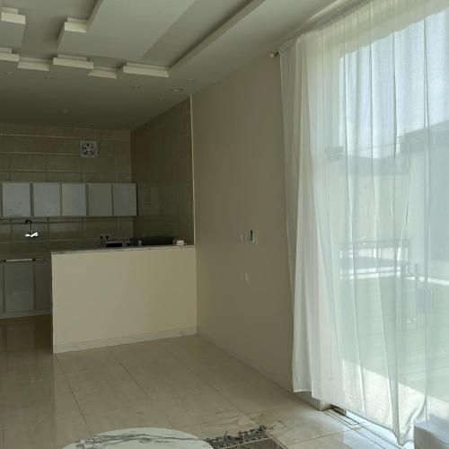 eine Küche mit einem großen Fenster und einem weißen Vorhang in der Unterkunft شاليهات حلم in Al Aqiq