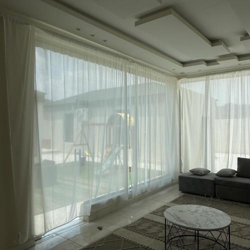 sala de estar con cortinas blancas, sofá y mesa en شاليهات حلم, en Al Aqiq