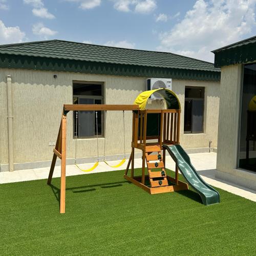 un parque infantil con un tobogán en el césped en شاليهات حلم, en Al Aqiq